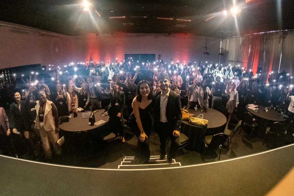 Salão do evento com o público de lanternas de celular acesas